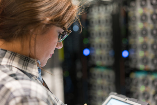 Close up from side of technician in server room looking at digit