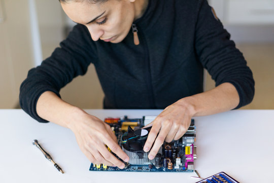 Woman repairing a motherboard of computer