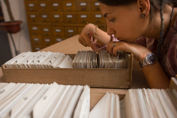 Young female student searching through library index