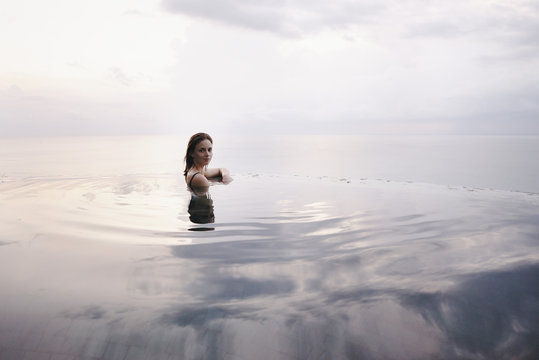 Young attractive woman relaxing in an infinity pool