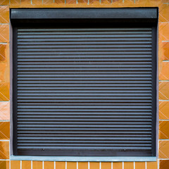 The texture of the window with blinds on the wall with ceramic tiles. Can be used as a background in interior design. Exterior of the facade of the house. Metal roller shutter for shop