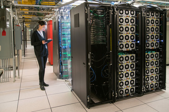 Backside of a bank of servers in a server room with technician