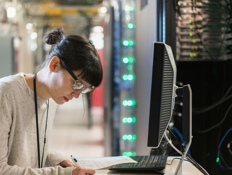 Close up of server room tech bent over paperwork