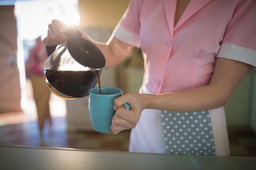 Fototapeta na wymiar Waitress pouring black coffee in mug at restaurant