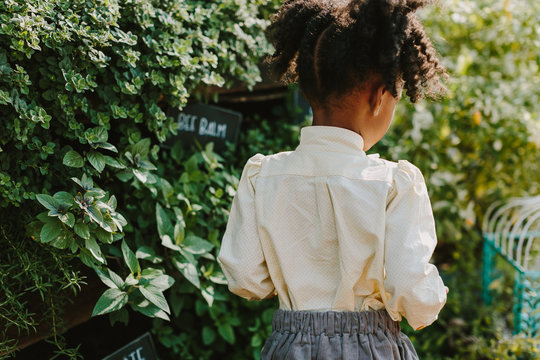 A little girl with pigtails roaming an outdoor garden