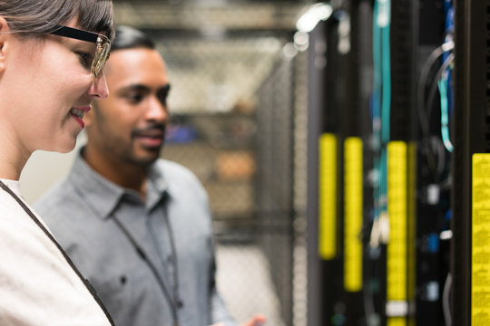 Two server room technicians looking at back of server