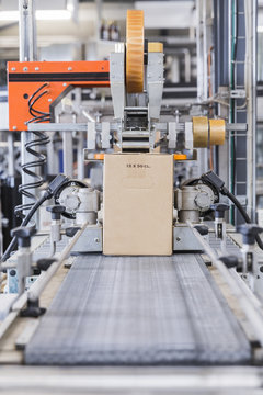 Cardboard box being sealed by machine in a factory