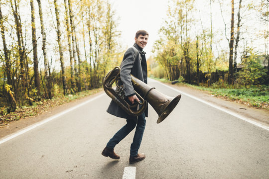 Man with tuba running away along the road