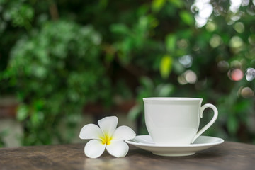 Fototapeta na wymiar Hot cup of coffee with white flower decor on table