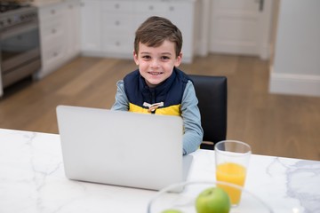 Boy using laptop in kitchen