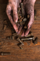 Woman hands holding bolts and washers on wooden background. Maintenance, service, construction, repair concept