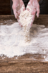 Baking craftsmanship. Woman hands making a dough from flour on wooden surface. Business bakery food industry concept