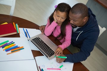 Father and daughter using laptop in kitchen