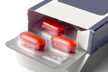 red pills blister pack in box on white background, macro
