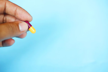 Hand Holding Capsule Over Blue Background