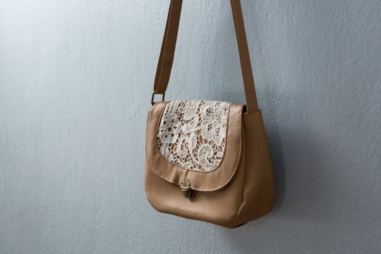 Stylish handbag hanging against wall