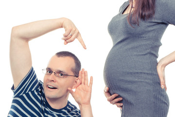 Happy father listening and showing belly of his wife, expecting for newborn