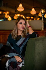 Young elegant plus size woman in cozy atmosphere restaurant. Lady wait on a date in romantic mood. Portrait in deep vintage tones