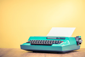 Retro old mint green typewriter with paper sheet on wooden table front gradient yellow background....