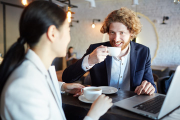 Young associates having coffee at break and discussing new business ideas