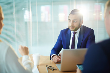 Attentive businessman listening to one of colleagues at start-up meeting during discussion of ideas