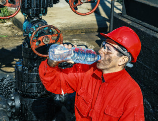 Oil Worker Drinks Water Beside Oil Well