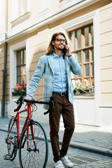 Man With Bicycle Calling On Phone While Walking On Street.