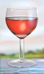 Glass of pink wine on garden table, shallow depth of field