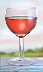 Glass of pink wine on garden table, shallow depth of field