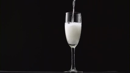 Champagne with bubbles is pouring in a classic glass on a black background - Powered by Adobe