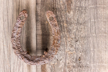 old, antique rusty horseshoe, fixed on nails on an old wooden surface