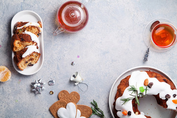 Slices of traditional christmas cake with dried fruits soaked in rum and sugar glaze. Teatime with heart-shaped ginger cookies. Christmas background with festive decoration. Copy space.