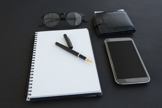 Spectacles, organizer, pen, mobile phone and wallet on