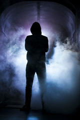 Silhouette of a man with a hood in blue light