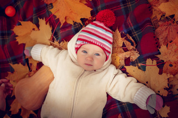 Little attractive baby playing in autumn park.