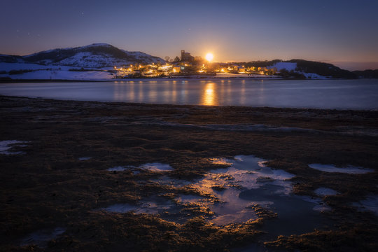 Moonset over Nanclares de Ganboa village in a frozen morning