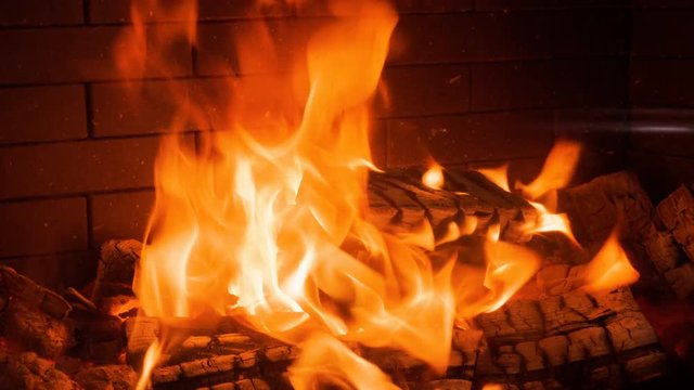 Home interior. Close-up shot of warm cozy burning fire in a brick fireplace. 4K
