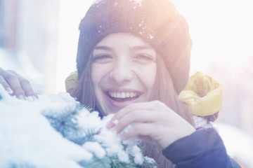 Young beautiful woman cheerfully rejoicing at snow in sunbeams. Fine winter day. (Christmas, new year, celebration concept)