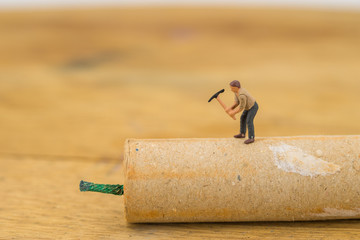 Concept miniature people destroying a Firecracker