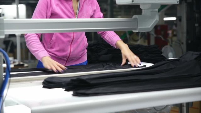 The woman-the inspector checks the quality of products on production line of hosiery.