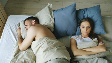 Top view of upset lying sleepless couple in bed offended because of quarrel