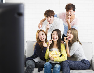 young group Sitting On Sofa Watching TV  show