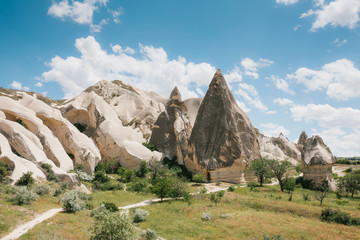 Beautiful view of the hills of Cappadocia. One of the sights of Turkey. The road passes by. A blue sky with clouds in the background.