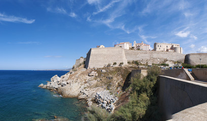 Fototapeta na wymiar Corsica, 03/09/2017: il Mar Mediterraneo e la spiaggia con vista sullo skyline dell'antica Cittadella di Calvi con le sue antiche mura 