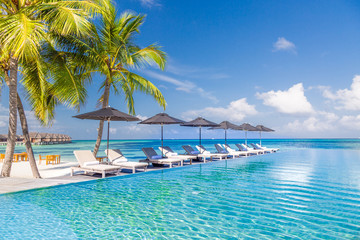 Luxury beach scene with sun chairs and loungers and the blue sea in the background in Maldives