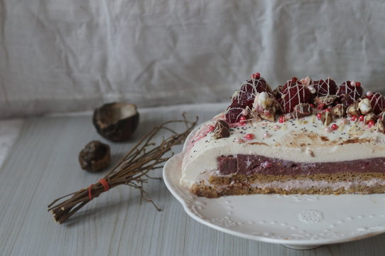 Gentle Muscovy cake with raspberry curd and poppy cakes, decorated with strawberries, chocolate, marshmallows and frosting on a light wooden background