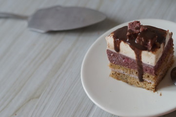 Gentle Muscovy cake with raspberry curd and poppy cakes, decorated with strawberries, chocolate, marshmallows and frosting on a light wooden background