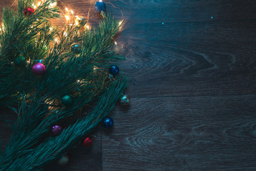 Christmas tree branches with Christmas decorations on a wooden background.