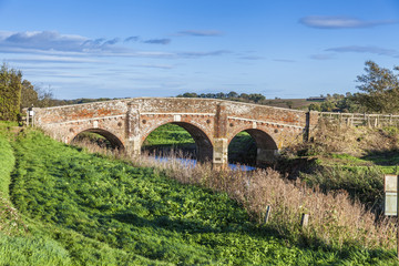 old bridge over Rother river on a sunny autumn day with green grass and blue sky