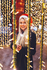 Beautiful young woman enjoying Christmas or New Year night on a city street. 